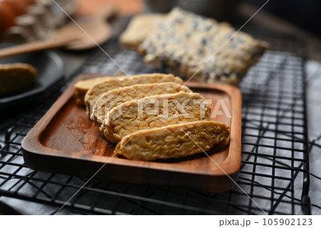 Sliced raw tempeh on wooden plate. Tempeh or Tempe made from fermented soybeans, vegetarian food Sliced raw tempeh on wooden plate. Tempeh or Tempe made from fermented soybeans, vegetarian food 105902123