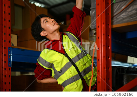 Upset male worker suffering from back pain while sitting on stairs in warehouse. Industrial and industrial workers concept 105902160