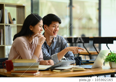Cheerful male and female students are working on academic project or preparing for exam together Cheerful male and female students are working on academic project or preparing for exam together 105902165