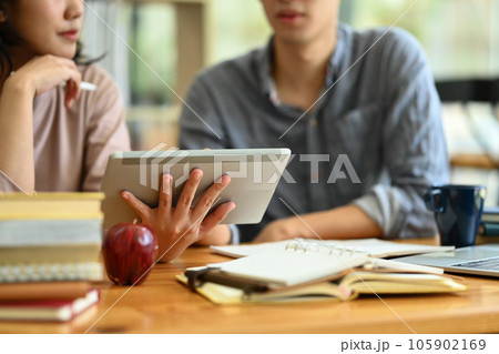 Cropped shot of college students using digital tablet, preparing for exam together in the campus 105902169