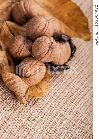 group of big walnuts with dry leaves on burlap on a wooden background 105904082