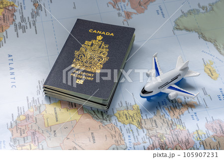 Calgary, Alberta, Canada. Aug 3, 2023. Canadian passport next to an airplane on a world map. Concept 105907231