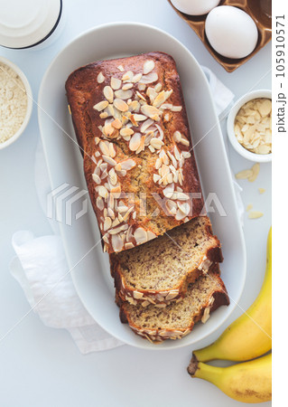 Banana bread with almonds on a white plate on a white background. Ingredients for home baking background. Banana bread with almonds on a white plate on a white background. Ingredients for home baking background. 105910571
