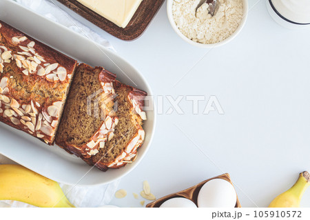 Banana bread with almonds on a white plate on a white background. Ingredients for home baking background. 105910572