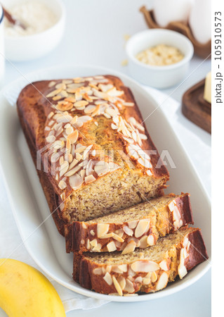 Banana bread with almonds on a white plate on white background. 105910573