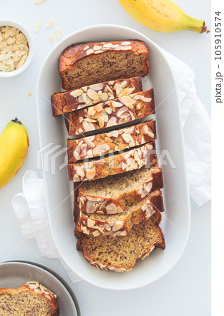Banana bread with almonds on a white plate on a white background. Ingredients for home baking background. 105910574