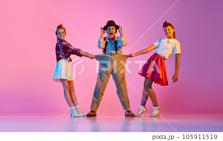 Children in stylish retro clothes making performance, dancing against pink studio background in neon light 105911519