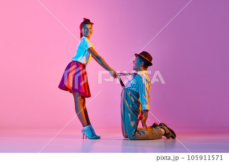 Friendship. Children making creative dance performance against pink studio background in neon light 105911571