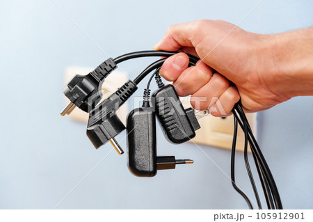 A bunch of disconnected electrical plugs with cables in a hand in room. Saving electricity concept A bunch of disconnected electrical plugs with cables in a hand in room. Saving electricity concept 105912901