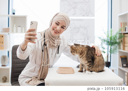Muslim lady taking selfie of animal patient at vet visit Muslim lady taking selfie of animal patient at vet visit 105913116