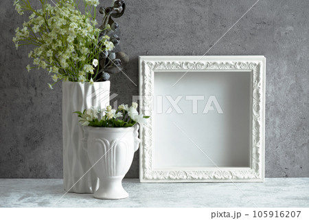 コンクリートの壁の前に飾られた白い木製フレームと花瓶 105916207