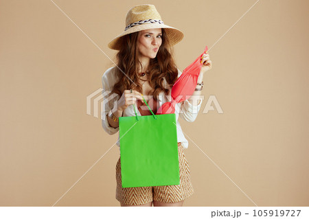 stylish 40 years old woman in blouse and shorts against beige 105919727