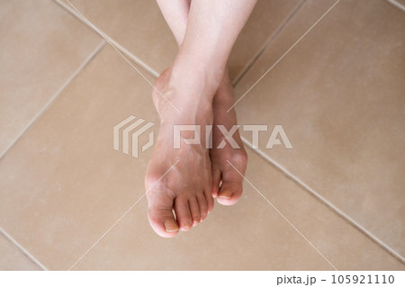 Hallux valgus on female legs on the background of laminate flooring. A bump on a woman's legs close-up. View from above 105921110