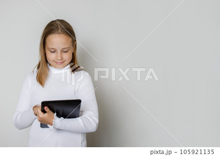Kid with tablet gadget against white studio wall background 105921135