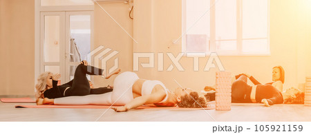 Happy middle aged well looking women, performing fascia exercises on floor using massage foam roller - tool to relieve tension in the back and relieve muscle pain. Female fitness yoga routine concept 105921159
