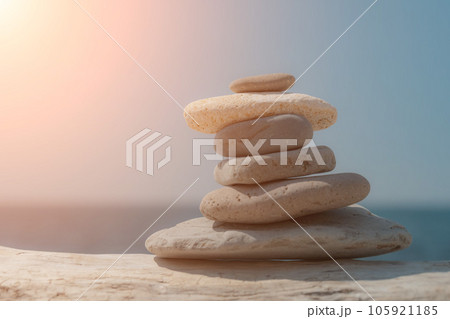 Pyramid stones on the seashore on a sunny day on the blue sea background. Happy holidays. Pebble beach, calm sea, travel destination. Concept of happy vacation on the sea, meditation, spa, calmness. Pyramid stones on the seashore on a sunny day on the blue sea background. Happy holidays. Pebble beach, calm sea, travel destination. Concept of happy vacation on the sea, meditation, spa, calmness. 105921185