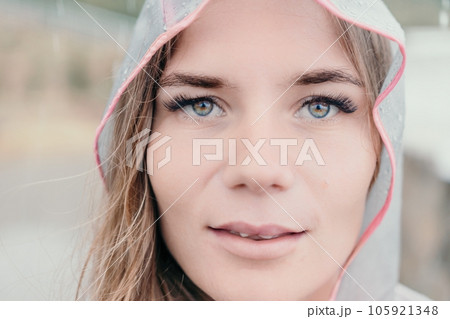 Woman rain umbrella. Happy woman portrait wearing a raincoat with transparent umbrella outdoors on rainy day in park near sea. Girl on the nature on rainy overcast day. Woman rain umbrella. Happy woman portrait wearing a raincoat with transparent umbrella outdoors on rainy day in park near sea. Girl on the nature on rainy overcast day. 105921348