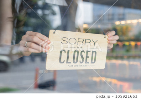 Female store owner turning close sign board of start up coffee shop cafe and restaurant through the door glass and closing the daily service Female store owner turning close sign board of start up coffee shop cafe and restaurant through the door glass and closing the daily service 105921663