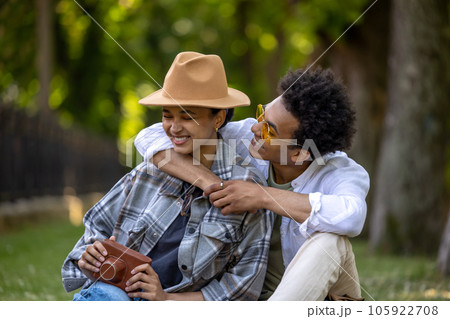 Young cute couple sitting on the grass and looking romantic Young cute couple sitting on the grass and looking romantic 105922708