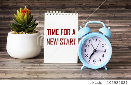 TIME FOR A NEW START text on notepad and wooden background with clock and cactus flower. 105922821