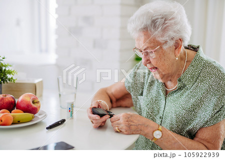 Diabetic senior patient checking her blood sugar level with fingerstick testing glucose meter. 105922939