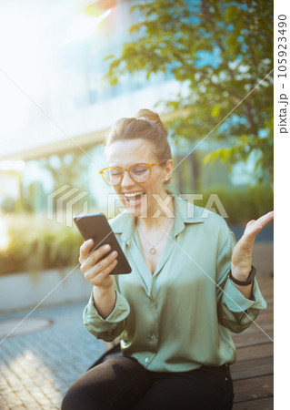woman worker in green blouse and eyeglasses using smartphone 105923490