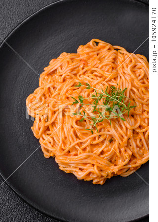Delicious fresh pasta consisting of thin noodles, red pesto rosso sauce with spices and herbs 105924170