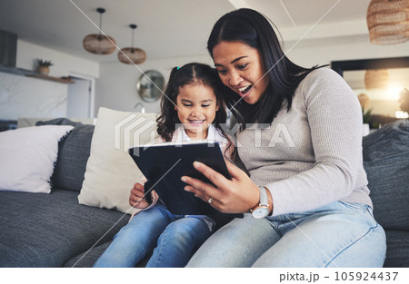 Tablet, surprise and a mother on the sofa with her daughter in the living room of their home together. Wow, family or children with a mother and girl looking at social media or a good news email 105924437