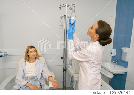 Professional doctor putting an IV drip to female patient intravenously in hospital ward Professional doctor putting an IV drip to female patient intravenously in hospital ward 105926444