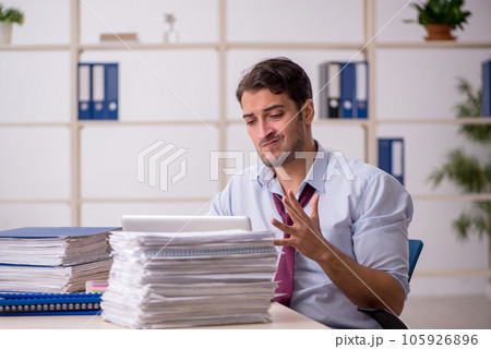 Young male employee and too much work in the office Young male employee and too much work in the office 105926896