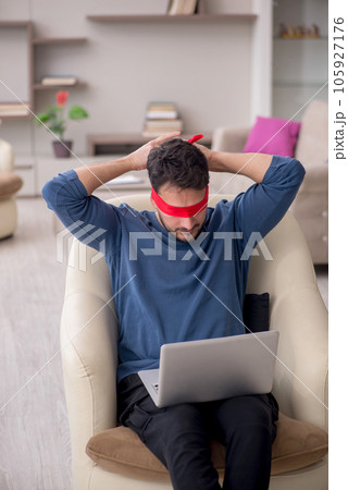 Blindfolded young male freelancer working from home 105927176