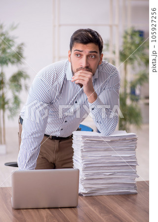 Young male employee and too much work in the office Young male employee and too much work in the office 105927256