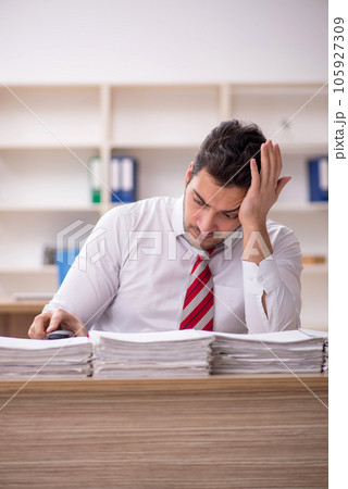 Young male employee and too much work in the office 105927309