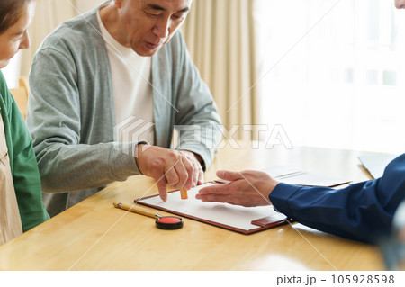 契約書に捺印をする夫婦 105928598