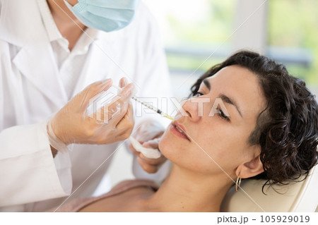 Woman getting procedure of injection contouring and for facial correction in clinic 105929019