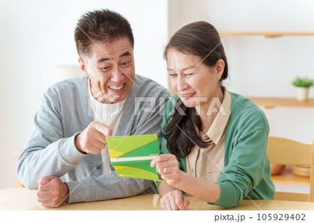 通帳を見て微笑むシニア夫婦 105929402