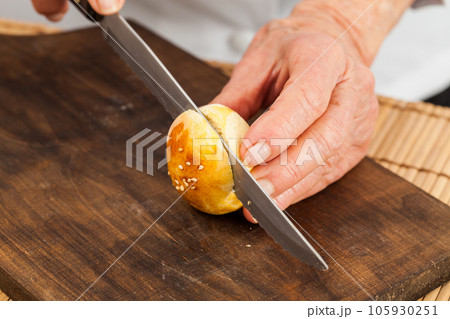 Cutting small bread buns for mini burgers. Step by step preparation of mini burgers. Homemade mini burgers for children or appetizers. Small hamburgers. 105930251