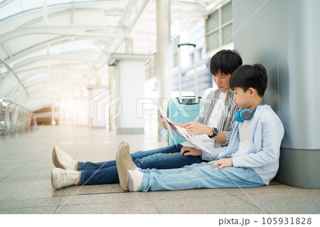 Happy cheerful Asian family traveling in the downtown together concept. Father looking at the railway station map with his son and pointing a forefinger on the map. Asian family tourist in city. 105931828