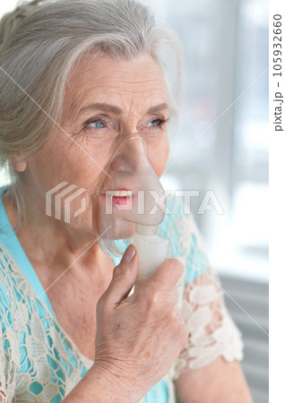 Portrait of an elderly woman using an inhaler 105932660