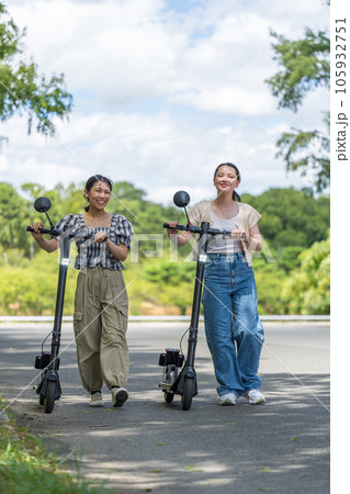 爽やかな夏空のもと電動キックボードで移動する若い女性｜電動キックボードイメージ 105932751