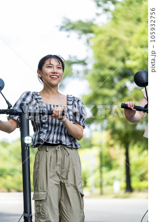 爽やかな夏空のもと電動キックボードで移動する若い女性｜電動キックボードイメージ 105932756