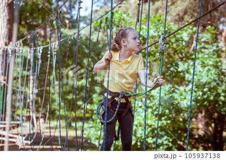 A child in a forest adventure park made of ropes. A child in a forest adventure park made of ropes. 105937138