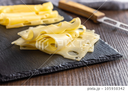 Slices of cheese on cutting board. 105938342