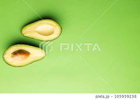 Close up of two halves of avocado and copy space on green background 105939238