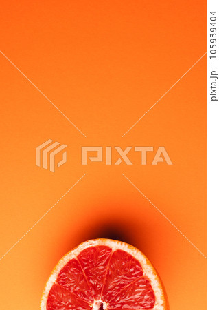 Close up of half of red grapefruit and copy space on orange background Close up of half of red grapefruit and copy space on orange background 105939404