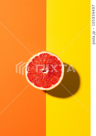 Close up of half of red grapefruit and copy space on orange and yellow background 105939497