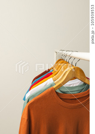 Multi coloured t shirts on hangers hanging from clothes rail and copy space on white background 105939553