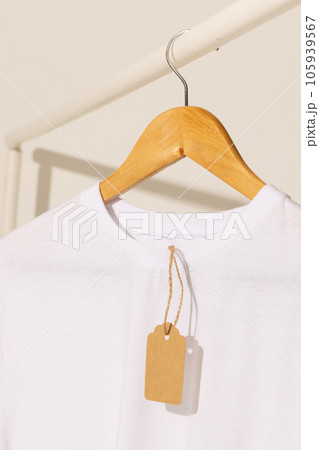White t shirt with tag hanging from clothes rack with copy space on white background 105939567