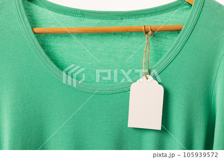 Green t shirt with tag on hanger with copy space on white background 105939572
