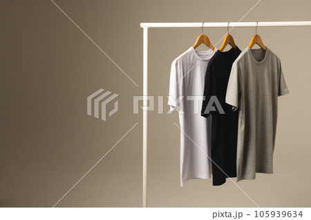 Three t shirts on hangers hanging from clothes rail and copy space on grey background 105939634